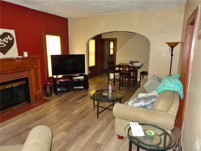 1915 S Elm St, Pittsburg, KS 66762 - living area featuring arched walkways, a textured ceiling, wood finished floors, and a brick fireplace