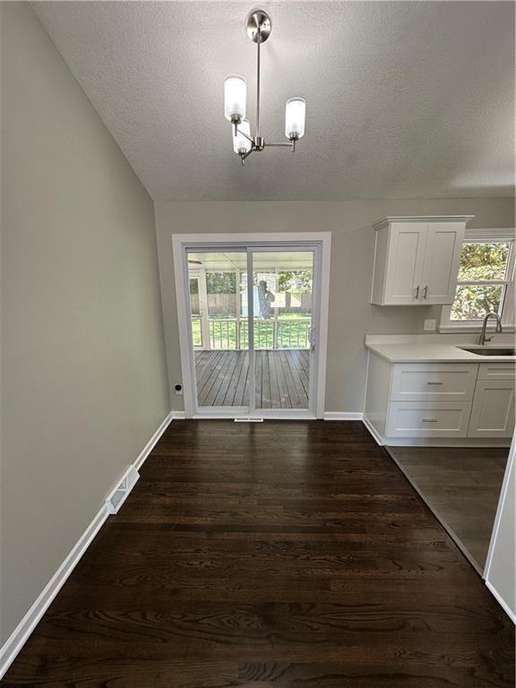 806 Lea Dr, Lees Summit, MO 64081 - unfurnished dining area featuring dark wood-style flooring, a textured ceiling, lofted ceiling, and a chandelier