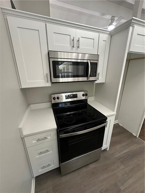 806 Lea Dr, Lees Summit, MO 64081 - kitchen featuring stainless steel appliances, dark wood-style flooring, light countertops, and white cabinets