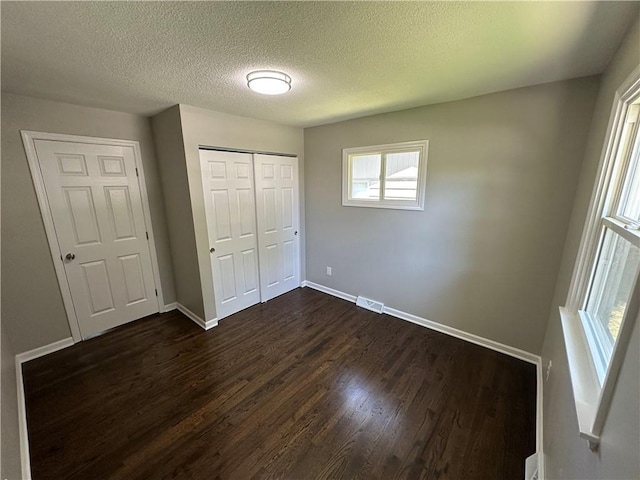 806 Lea Dr, Lees Summit, MO 64081 - unfurnished bedroom with dark wood-style floors, a textured ceiling, and a closet
