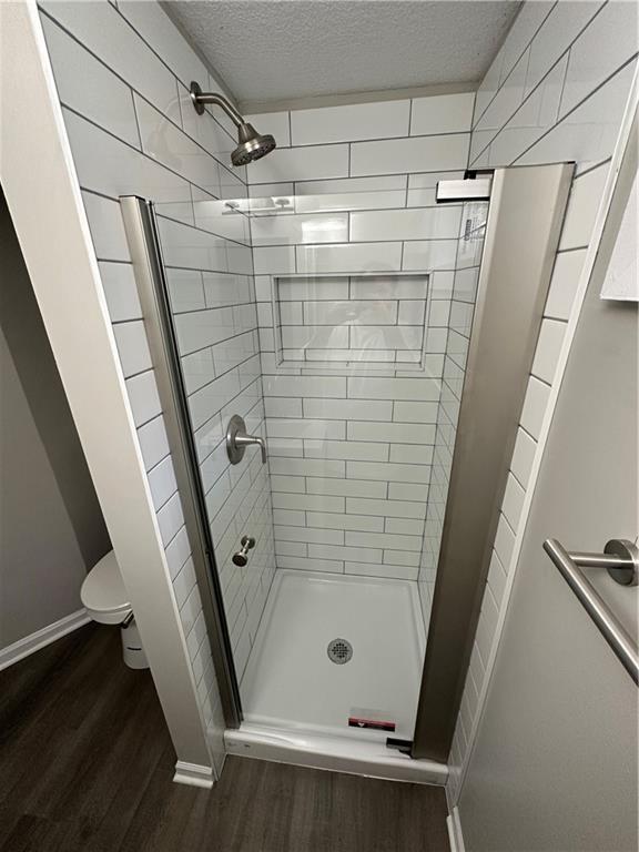 806 Lea Dr, Lees Summit, MO 64081 - full bath featuring wood finished floors, a shower stall, and a textured ceiling