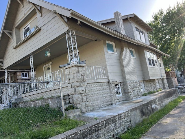 144 N Brighton Ave, Kansas City, MO 64123 - view of side of home with a porch, a chimney, and stone siding