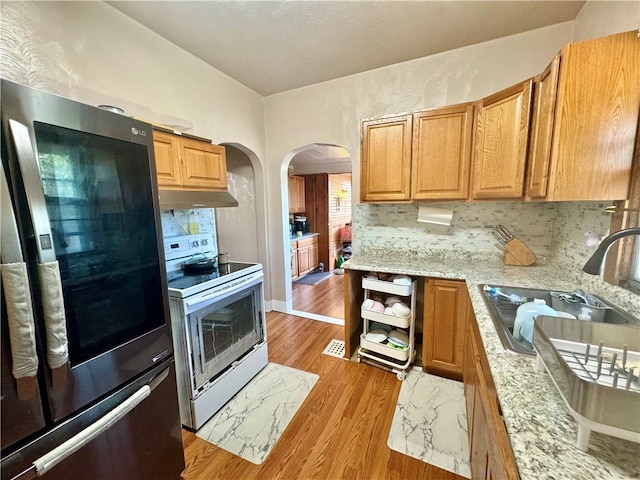 144 N Brighton Ave, Kansas City, MO 64123 - kitchen with smart refrigerator, electric stove, arched walkways, under cabinet range hood, and light wood finished floors