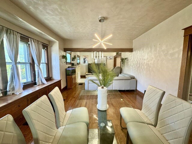 144 N Brighton Ave, Kansas City, MO 64123 - living room featuring wood finished floors, a chandelier, and a textured ceiling