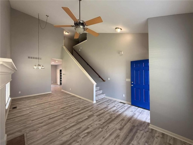 8808 NE 97th St, Kansas City, MO 64157 - unfurnished living room with stairs, high vaulted ceiling, a ceiling fan, wood finished floors, and a fireplace