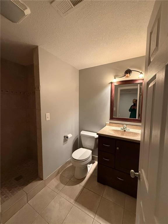 8808 NE 97th St, Kansas City, MO 64157 - full bathroom with a tile shower, vanity, tile patterned floors, and a textured ceiling