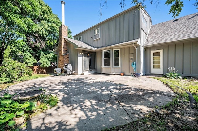 109 NE Locust St, Blue Springs, MO 64014 - rear view of house featuring board and batten siding, roof with shingles, a chimney, and concrete driveway