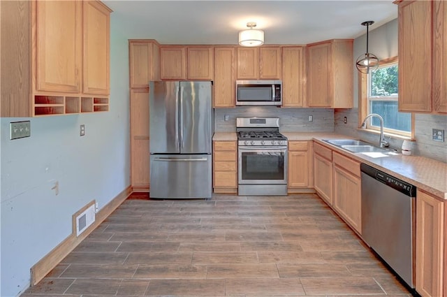 1700 S Pearl St, Independence, MO 64055 - kitchen with stainless steel appliances, light brown cabinetry, light countertops, tasteful backsplash, and light wood finished floors