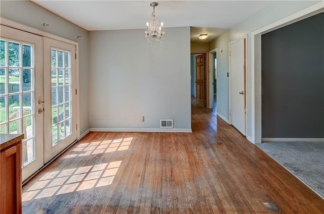 1700 S Pearl St, Independence, MO 64055 - unfurnished dining area with a chandelier, plenty of natural light, wood finished floors, and french doors