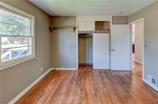 1700 S Pearl St, Independence, MO 64055 - unfurnished bedroom featuring light wood finished floors, multiple windows, and a closet