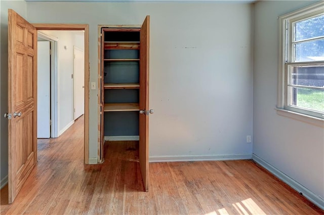 1700 S Pearl St, Independence, MO 64055 - unfurnished bedroom with light wood finished floors, multiple windows, and a closet