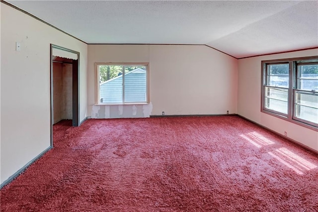 1700 S Pearl St, Independence, MO 64055 - unfurnished bedroom with vaulted ceiling, carpet floors, and a textured ceiling