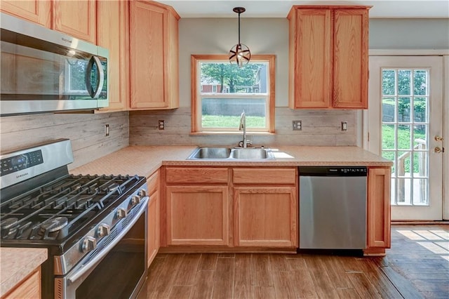 1700 S Pearl St, Independence, MO 64055 - kitchen with appliances with stainless steel finishes, light wood finished floors, light countertops, hanging light fixtures, and light brown cabinetry