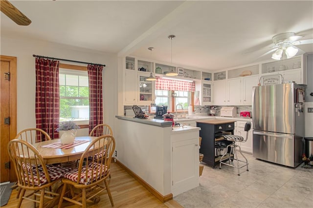 328 E 4th St, Lawson, MO 64062 - kitchen with freestanding refrigerator, white cabinets, a peninsula, glass insert cabinets, and a ceiling fan