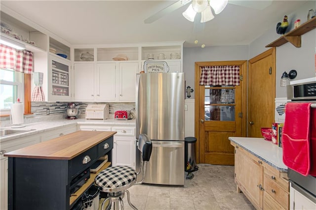 328 E 4th St, Lawson, MO 64062 - kitchen with freestanding refrigerator, butcher block countertops, a ceiling fan, white cabinetry, and tasteful backsplash