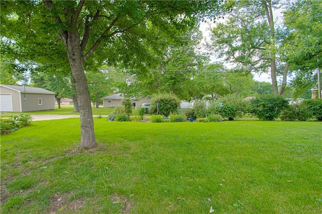 328 E 4th St, Lawson, MO 64062 - view of grassy yard with a garage and view of wooded area