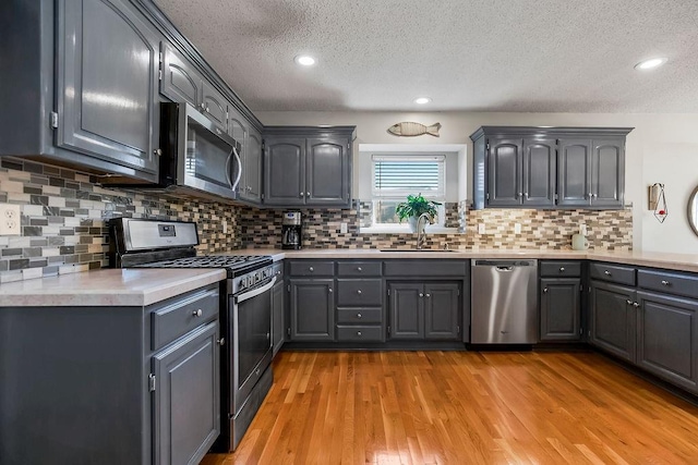1311 Honeysuckle Ct, Liberty, MO 64068 - kitchen with appliances with stainless steel finishes, a textured ceiling, light countertops, gray cabinets, and light wood finished floors
