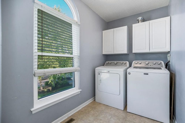 1311 Honeysuckle Ct, Liberty, MO 64068 - laundry area with washing machine and clothes dryer, cabinet space, a textured ceiling, and light tile patterned floors