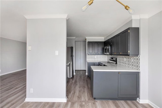 2525 Main St Unit 305, Kansas City, MO 64108 - kitchen featuring stainless steel appliances, light countertops, light wood-style flooring, tasteful backsplash, and a peninsula