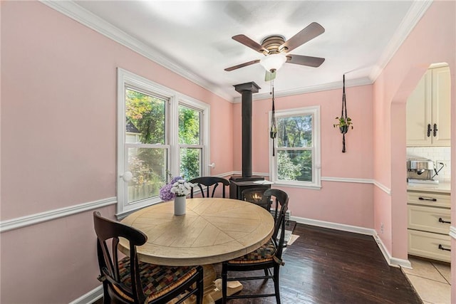5147 Maple Ave, Mission, KS 66202 - dining space featuring healthy amount of natural light, a wood stove, a ceiling fan, crown molding, and light wood-style floors