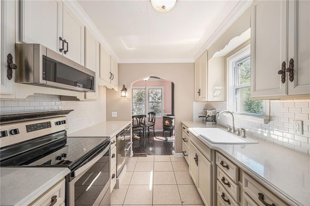 5147 Maple Ave, Mission, KS 66202 - kitchen featuring stainless steel appliances, arched walkways, healthy amount of natural light, backsplash, and ornamental molding