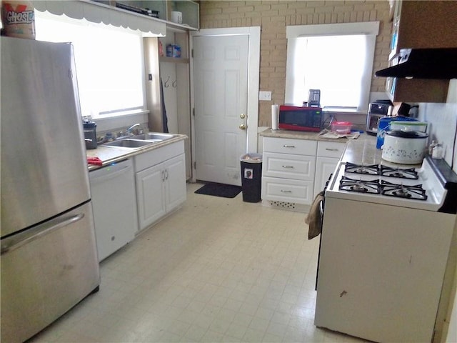 1909 S Broadway St, Pittsburg, KS 66762 - kitchen featuring white appliances, extractor fan, plenty of natural light, white cabinetry, and brick wall