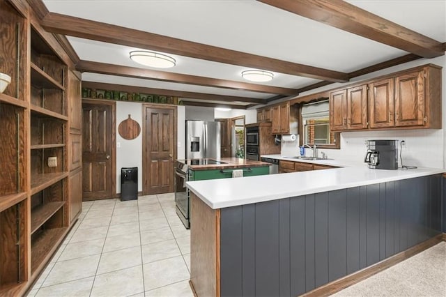 601 Darrow St, Warrensburg, MO 64093 - kitchen with appliances with stainless steel finishes, beamed ceiling, a peninsula, brown cabinetry, and a center island