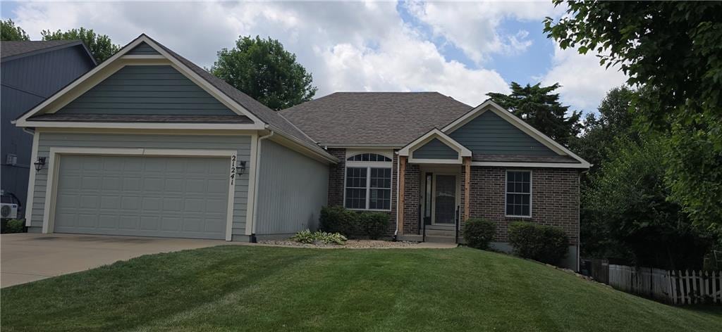 21241 W 123rd St, Olathe, KS 66061 - ranch-style house featuring a front yard, concrete driveway, an attached garage, and brick siding