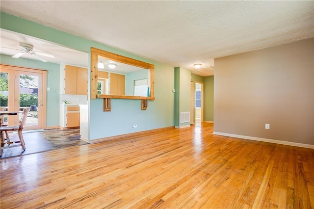1504 Oak Hill Ave, Lawrence, KS 66044 - unfurnished living room with light wood-style floors, ceiling fan, french doors, and a textured ceiling