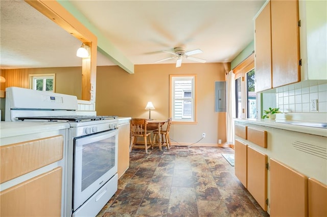 1504 Oak Hill Ave, Lawrence, KS 66044 - kitchen with white gas stove, ceiling fan, light countertops, dark stone finish floors, and tasteful backsplash