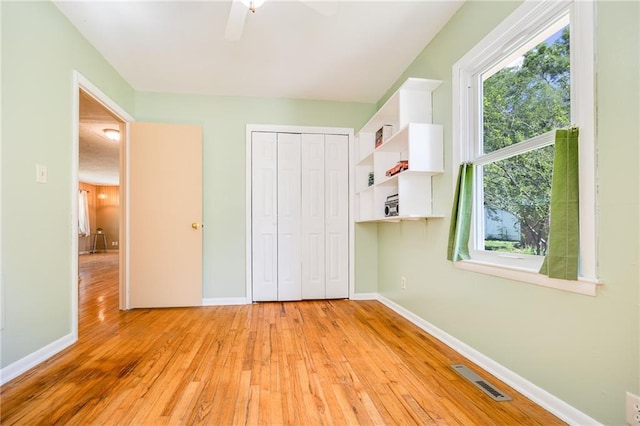 1504 Oak Hill Ave, Lawrence, KS 66044 - unfurnished bedroom featuring light wood-type flooring, multiple windows, a closet, and ceiling fan