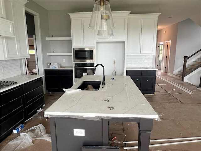 1709 SW Arbor Park Dr, Lees Summit, MO 64082 - kitchen with stainless steel appliances, decorative backsplash, white cabinetry, and a kitchen island with sink