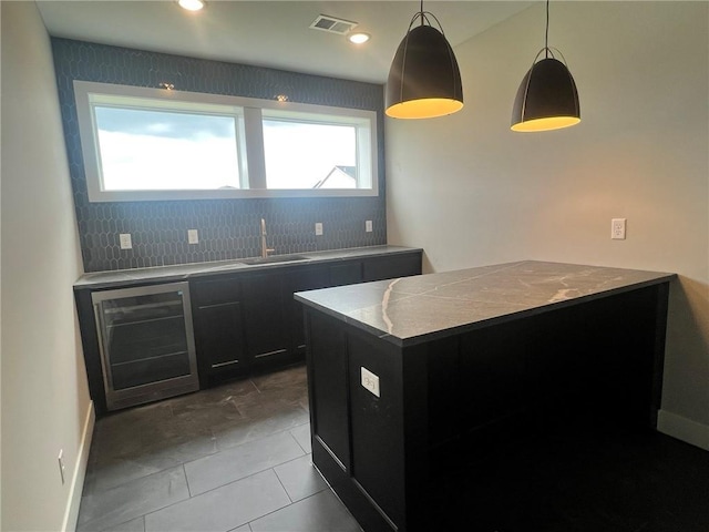 1709 SW Arbor Park Dr, Lees Summit, MO 64082 - kitchen featuring beverage cooler, dark cabinetry, a peninsula, decorative light fixtures, and backsplash