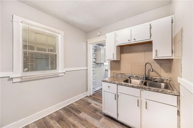 3842 E 68th Ter, Kansas City, MO 64132 - kitchen featuring wood finished floors, backsplash, white cabinetry, and a textured ceiling
