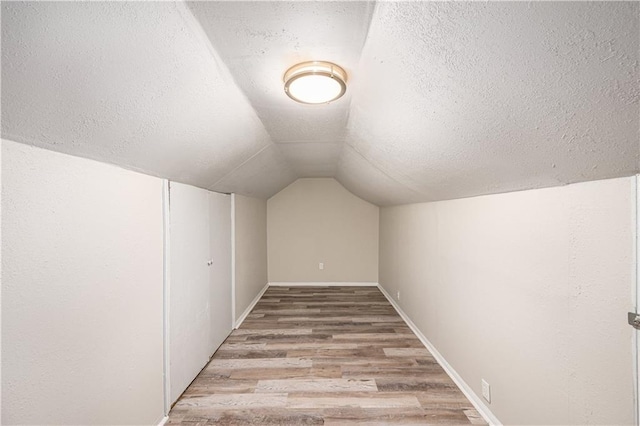 3842 E 68th Ter, Kansas City, MO 64132 - additional living space featuring wood finished floors, a textured ceiling, and vaulted ceiling