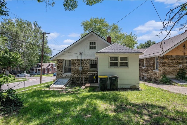 3842 E 68th Ter, Kansas City, MO 64132 - rear view of house featuring a lawn, a chimney, stone siding, and a shingled roof