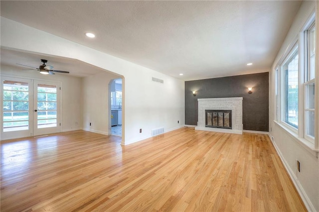 6605 Willow Ave, Raytown, MO 64133 - unfurnished living room featuring light wood-style floors, plenty of natural light, a brick fireplace, and recessed lighting