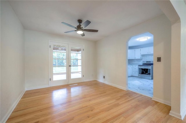 6605 Willow Ave, Raytown, MO 64133 - empty room featuring light wood-type flooring, a ceiling fan, arched walkways, and french doors