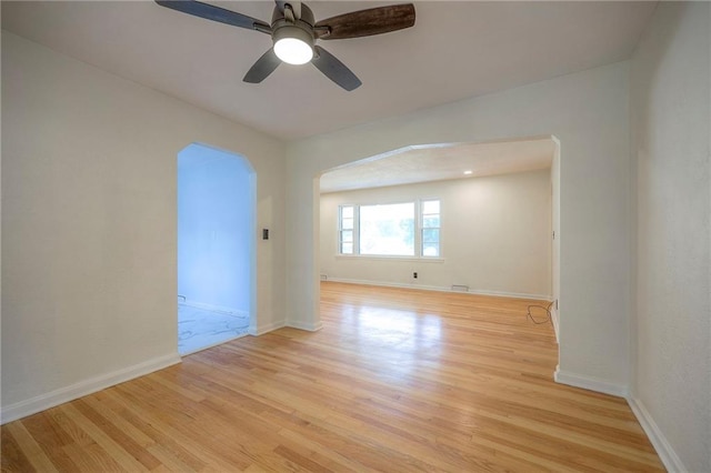6605 Willow Ave, Raytown, MO 64133 - empty room featuring light wood-type flooring, a ceiling fan, and arched walkways
