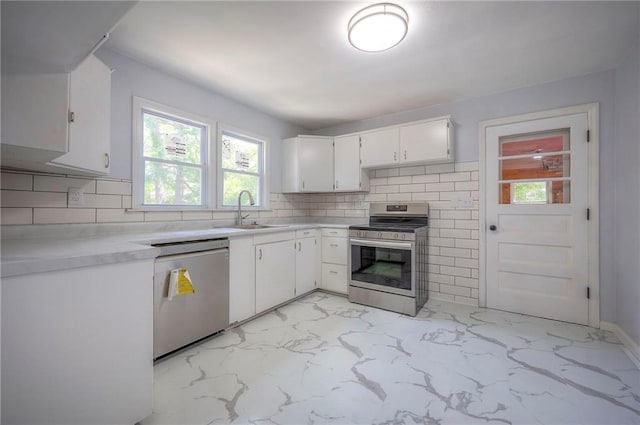 6605 Willow Ave, Raytown, MO 64133 - kitchen with stainless steel appliances, light marble finish flooring, light countertops, white cabinets, and backsplash