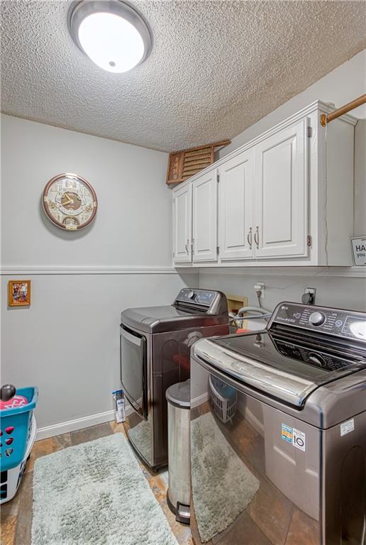 440 41p Rd, Clinton, MO 64735 - laundry area featuring washing machine and clothes dryer, cabinet space, and a textured ceiling