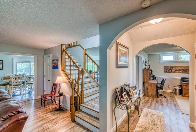 440 41p Rd, Clinton, MO 64735 - staircase featuring wood finished floors, a textured ceiling, and arched walkways