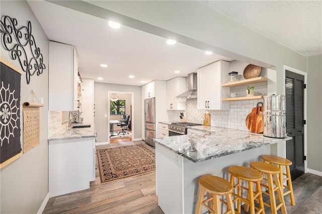 12419 Askew Dr, Grandview, MO 64030 - kitchen featuring stainless steel appliances, wall chimney exhaust hood, a peninsula, tasteful backsplash, and light stone counters