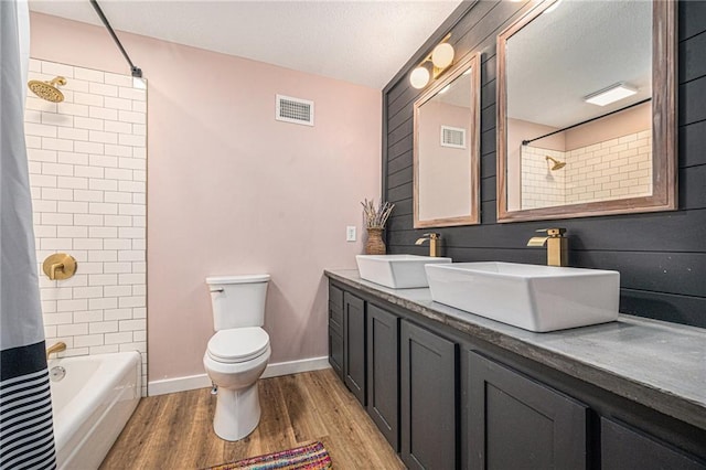 12419 Askew Dr, Grandview, MO 64030 - full bath featuring wood finished floors, double vanity, shower / bath combo, and a textured ceiling