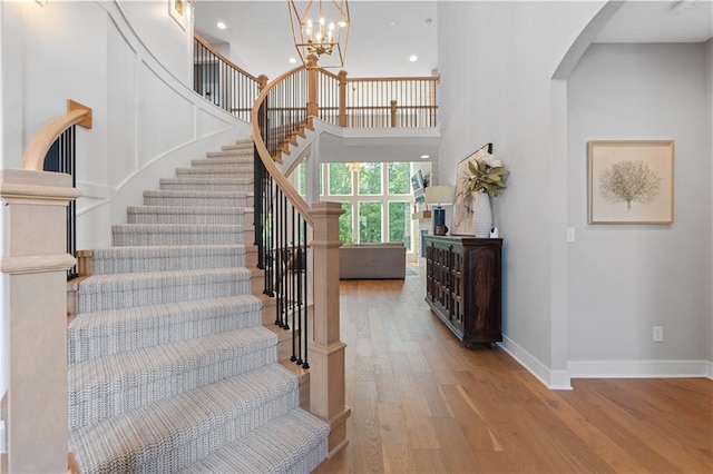 23717 W 118th Ter, Olathe, KS 66061 - stairs featuring arched walkways, wood finished floors, a chandelier, recessed lighting, and a towering ceiling