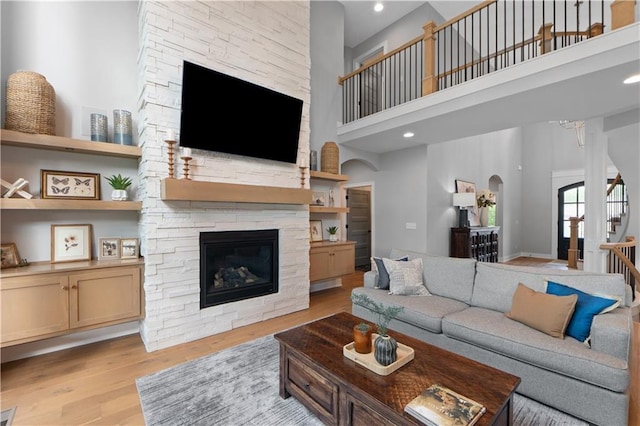 23717 W 118th Ter, Olathe, KS 66061 - living area featuring a high ceiling, arched walkways, a fireplace, light wood-style floors, and stairway