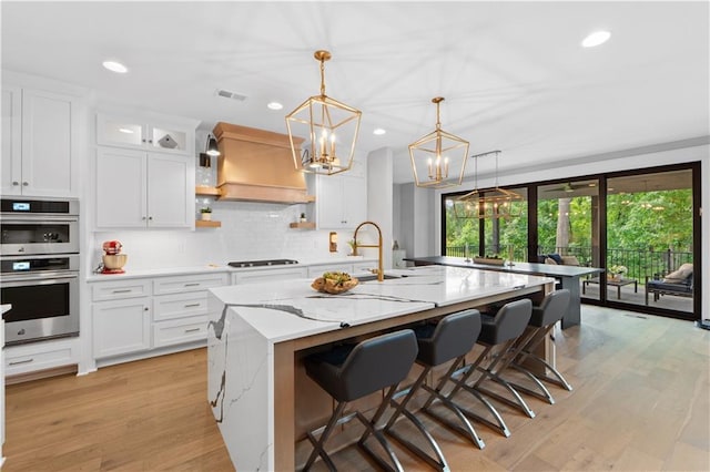 23717 W 118th Ter, Olathe, KS 66061 - kitchen featuring double oven, a chandelier, an island with sink, white cabinets, and recessed lighting