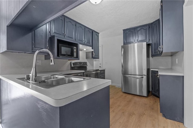 600 W Powahatan Ct, Independence, MO 64056 - kitchen with stainless steel appliances, a peninsula, light wood-type flooring, light countertops, and under cabinet range hood