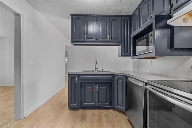 600 W Powahatan Ct, Independence, MO 64056 - kitchen featuring stainless steel appliances, ventilation hood, light wood-type flooring, light countertops, and a textured ceiling