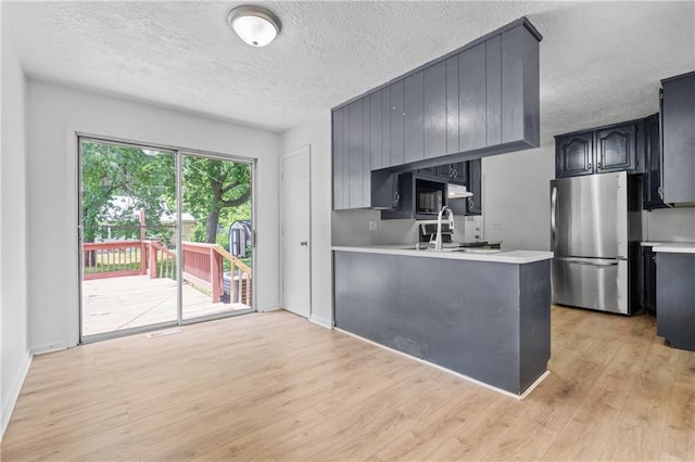 600 W Powahatan Ct, Independence, MO 64056 - kitchen with freestanding refrigerator, light countertops, a textured ceiling, light wood-style floors, and a peninsula